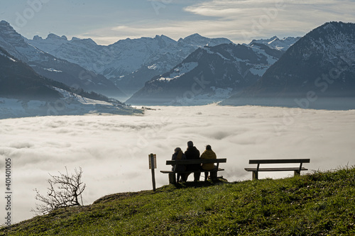 Drei Personen auf einer Sitzbank geniessen die Sonne über dem Nebelmeer, ob Ennetbürgen, Kanton Nidwalden, Schweiz © tauav