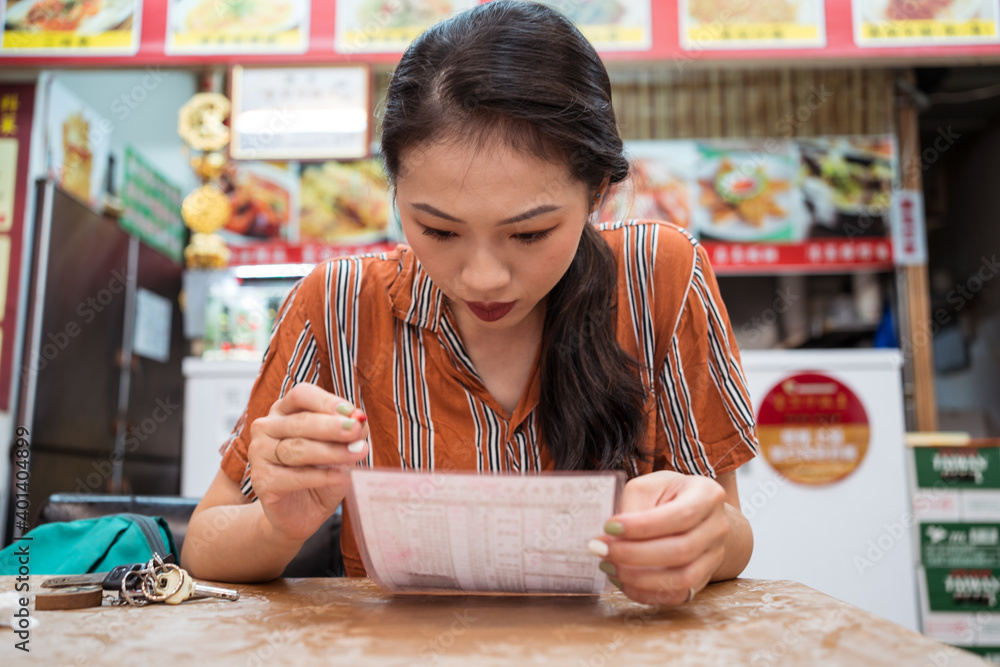 Young Asian woman looking at restaurant menu