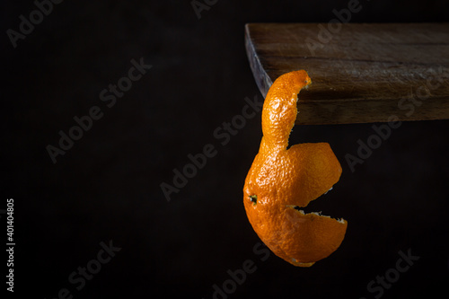 The tangerine peel hangs from the wooden surface. Citrus fruit. Mandarin zest