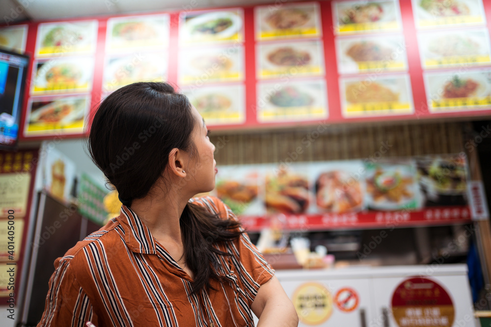 Young Asian woman looking at restaurant menu