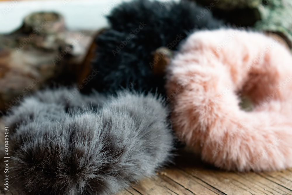 Fashionable and stylish fur elastic bands for hair and hairstyles. Multi-colored artificial and natural cannons on a natural wooden background Fashionable and stylish fur elastic bands for hair and hairstyles. Multi-colored artificial and natural cannons on a natural wooden background