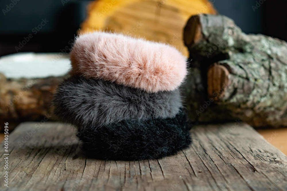 Fashionable and stylish fur elastic bands for hair and hairstyles. Multi-colored artificial and natural cannons on a natural wooden background Fashionable and stylish fur elastic bands for hair and hairstyles. Multi-colored artificial and natural cannons on a natural wooden background