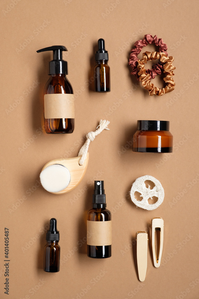Set of amber glass bottles with blank labels and female bathroom accessories on brown background. SPA cosmetics set. Flat lay, top view Set of amber glass bottles with blank labels and female bathroom accessories on brown background. SPA cosmetics set. Flat lay, top view