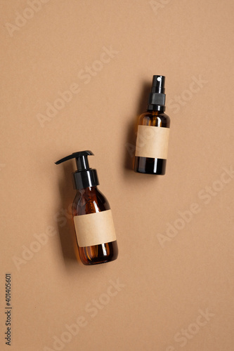 Amber glass bottles mockup with blank labels on brown background. Pump and spray containers packaging design. Bathroom cosmetics. Flat lay, top view