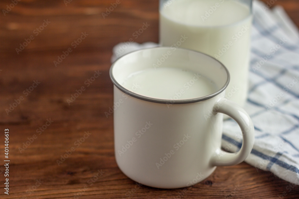 A bottle of milk and a mug of milk on a wooden table. A bottle of milk and a mug of milk on a wooden table.