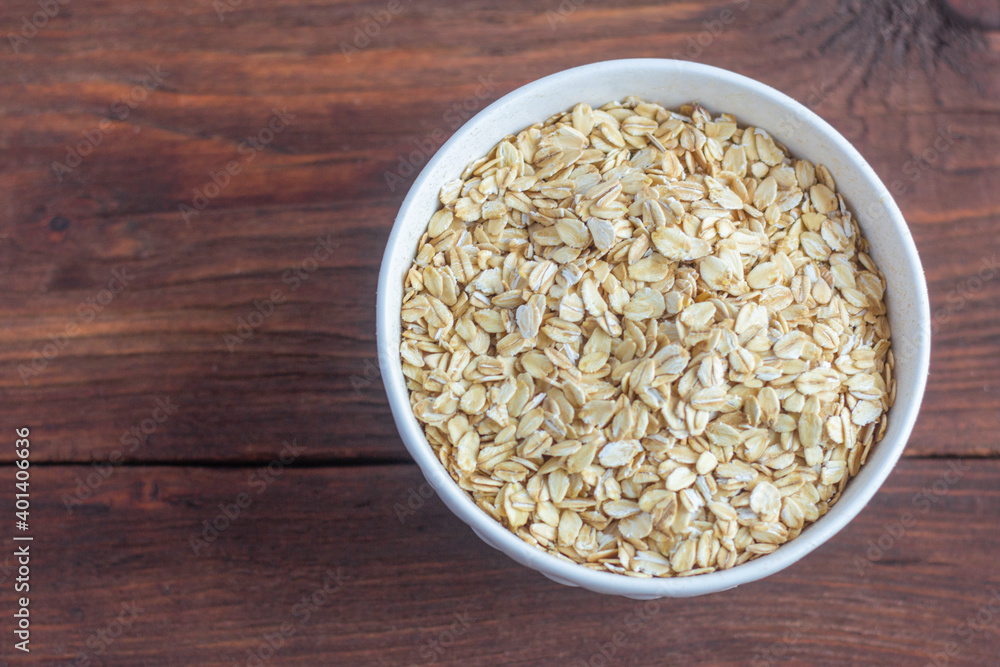 Traditional large oat flakes in a bowl on a wooden background with a copy of the space.The view from the top. Traditional large oat flakes in a bowl on a wooden background with a copy of the space.The view from the top.
