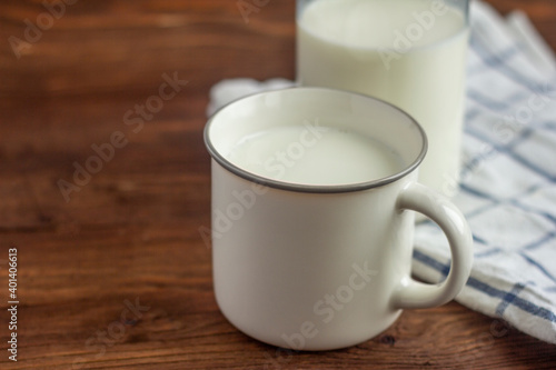 A bottle of milk and a mug of milk on a wooden table.