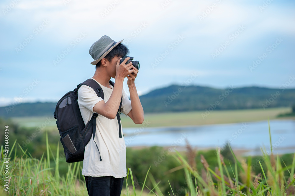 Obraz premium Young Asian man traveler with backpack taking a photo and looking at amazing lake. Travel holiday relaxation concept