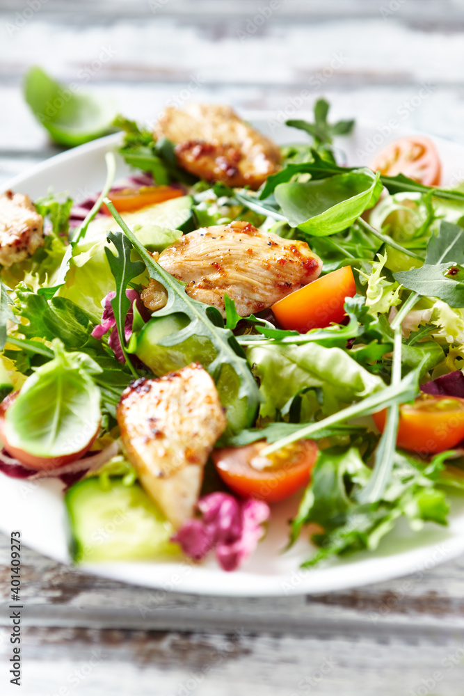 Salad with Chicken Breast, Cherry Tomatoes, Cucumber, Rocket and fresh Basil. Bright wooden background. Close up. Salad with Chicken Breast, Cherry Tomatoes, Cucumber, Rocket and fresh Basil. Bright wooden background. Close up.