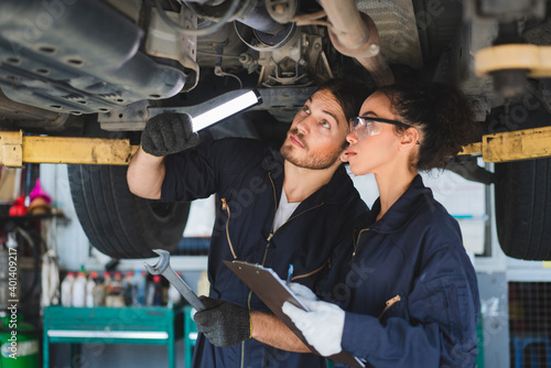 Two mechanics man and woman checking and repair maintenance a car in auto service garage