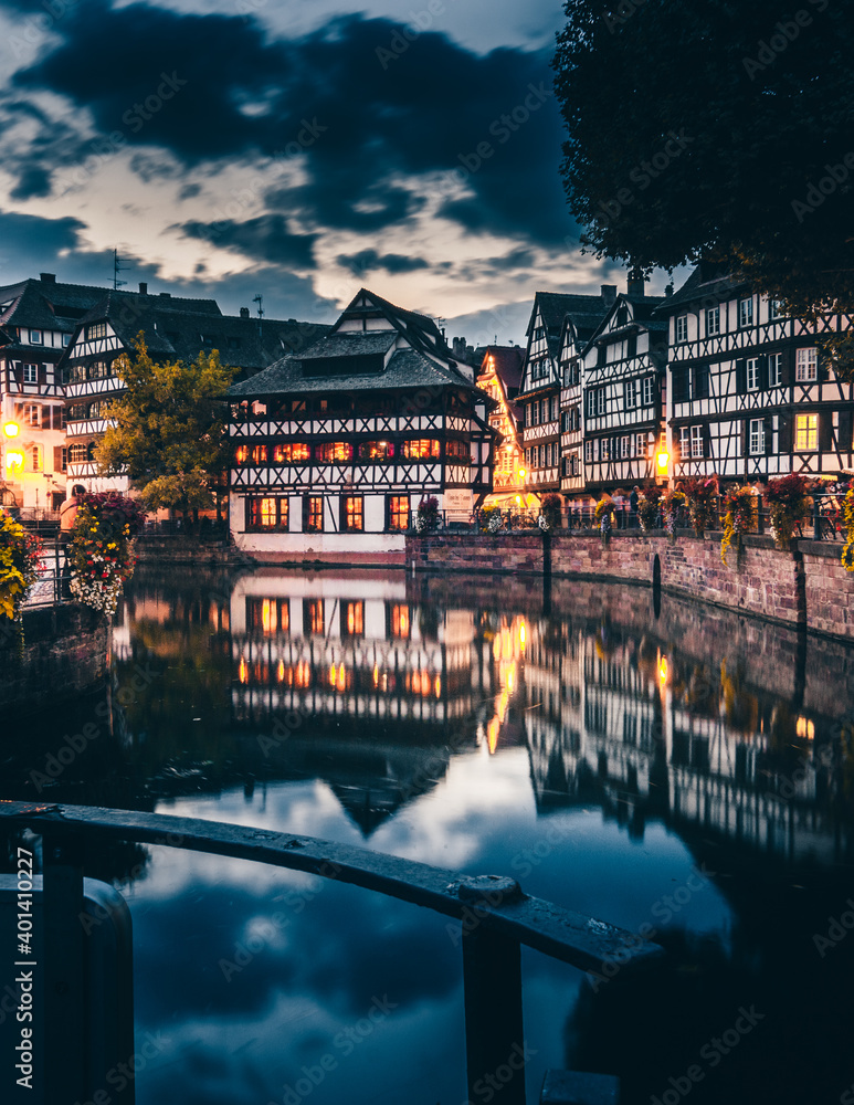the beautiful Strasbourg in the evening with reflection on the water and beautiful half-timbered houses with flowers. City panorama