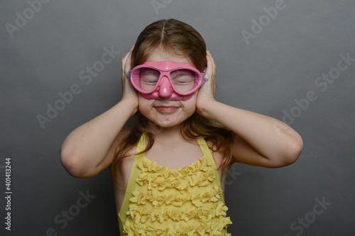 little girl in yellow swimsuit and pink mask. ear barotrauma