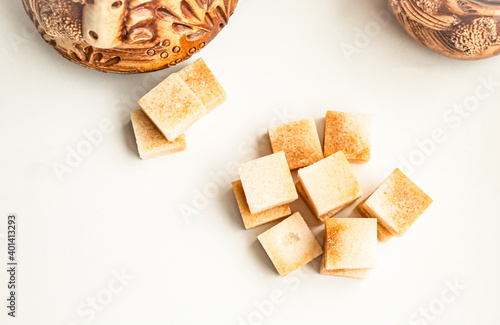 Cubes of brown cane sugar near ceramic utensils