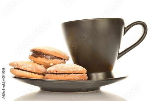 Several delicious shortbread biscotti cookies on a saucer with a cup, close-up, isolated on white.