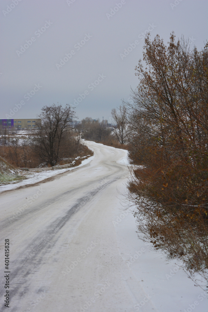 A large, high mountain along a well-worn road covered with white fluffy snow with trees and bushes at the end of December. A large, high mountain along a well-worn road covered with white fluffy snow with trees and bushes at the end of December.