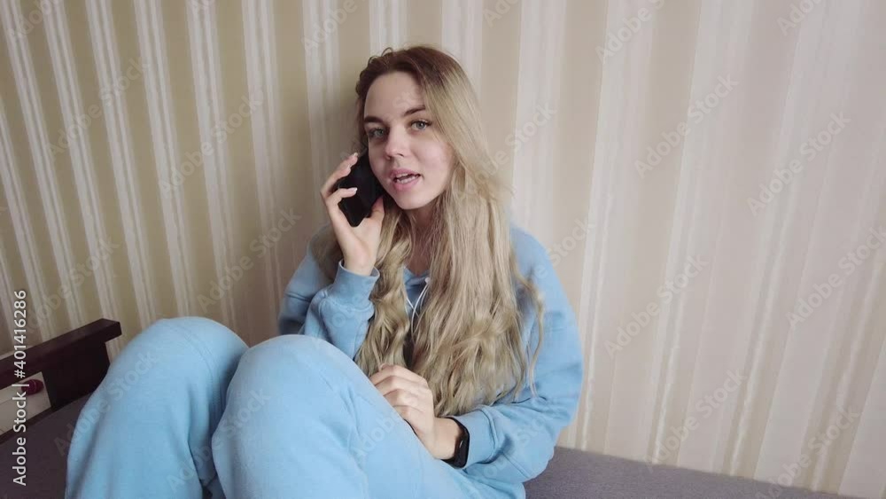 A young girl is talking on a mobile phone, sitting on the couch and looks very happy, having a good conversation A young girl is talking on a mobile phone, sitting on the couch and looks very happy, having a good conversation