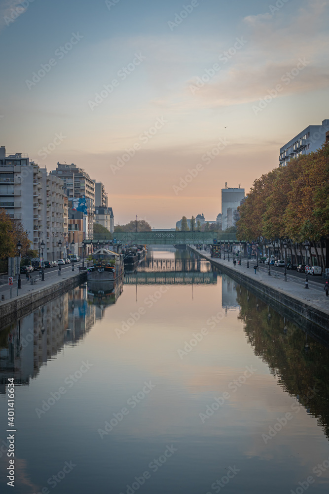 Paris, France - 11 07 2020: People sitting and walking alongside Bassin de la Villette near the lifting bridge of Flanders at sunset