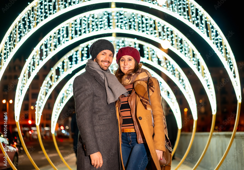 Winter portrait of a caucasian couple next to the christmas lights of the city, lifestyle