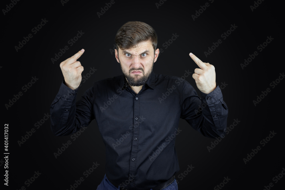 a man in a black shirt and on a black background shows his middle fingers makes obscene gestures a man in a black shirt and on a black background shows his middle fingers makes obscene gestures