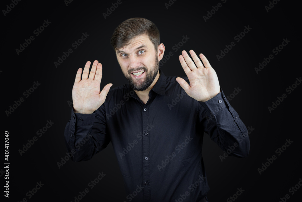 a man in a black shirt and on a black background shows the palms of his hands gestures