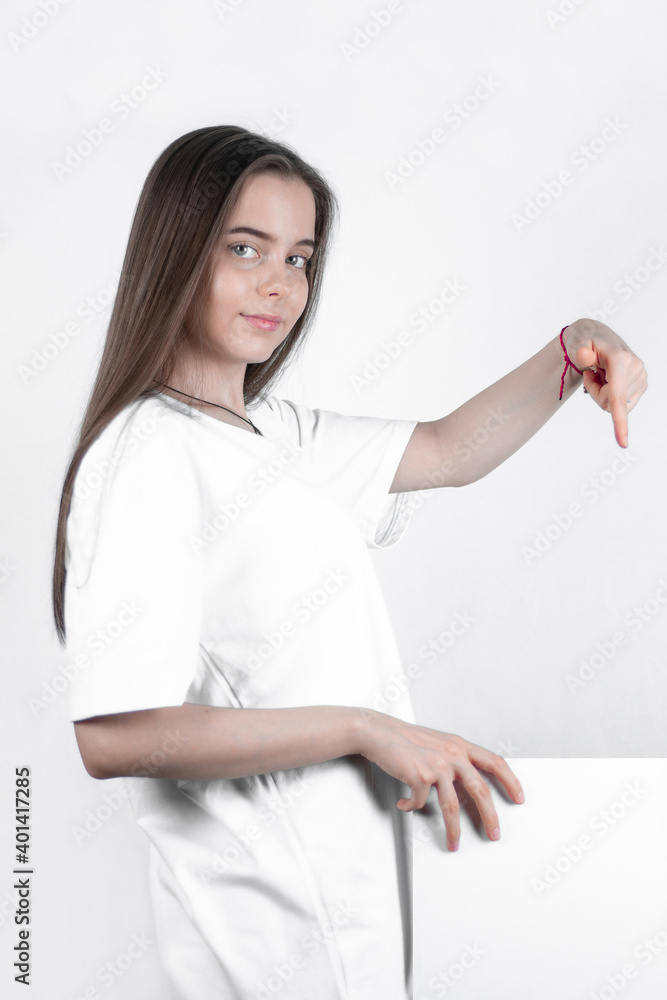 Nice teen girl shows down a finger on a white poster. Nice teen girl shows down a finger on a white poster.