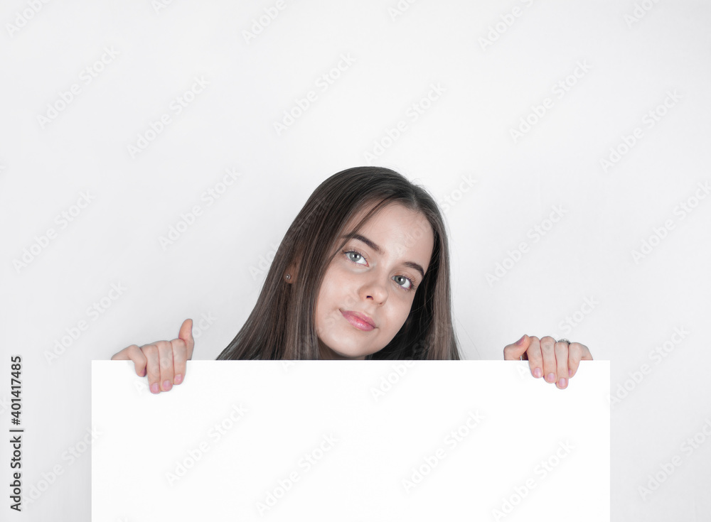 A pretty girl teenager demonstrates with her hands a large white board. A pretty girl teenager demonstrates with her hands a large white board.