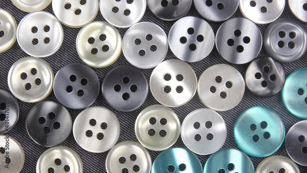 Plastic shiny buttons for clothes on a fabric background. Fashion and clothing. Factory industry Plastic shiny buttons for clothes on a fabric background. Fashion and clothing. Factory industry