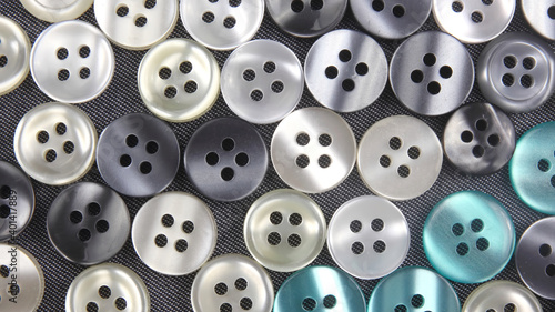 Plastic shiny buttons for clothes on a fabric background. Fashion and clothing. Factory industry