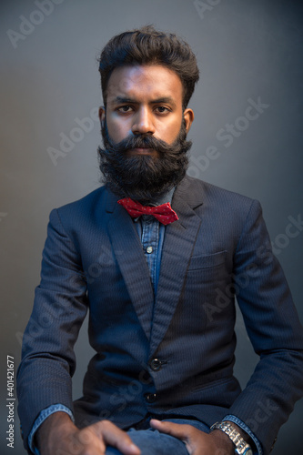Photography Portrait of young man posing with beard in suit on gray background