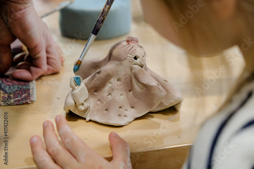A child paints his clay figurine in a workshop at a modeling lesson.