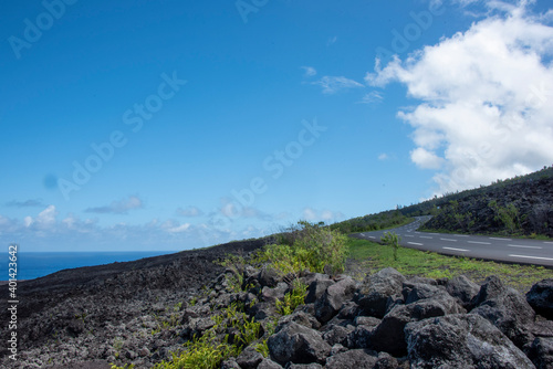 Volcanic and sea landscape with a road on the flanks of the Piton de la Fournaise in Réunion island, tropical active volcano, France.