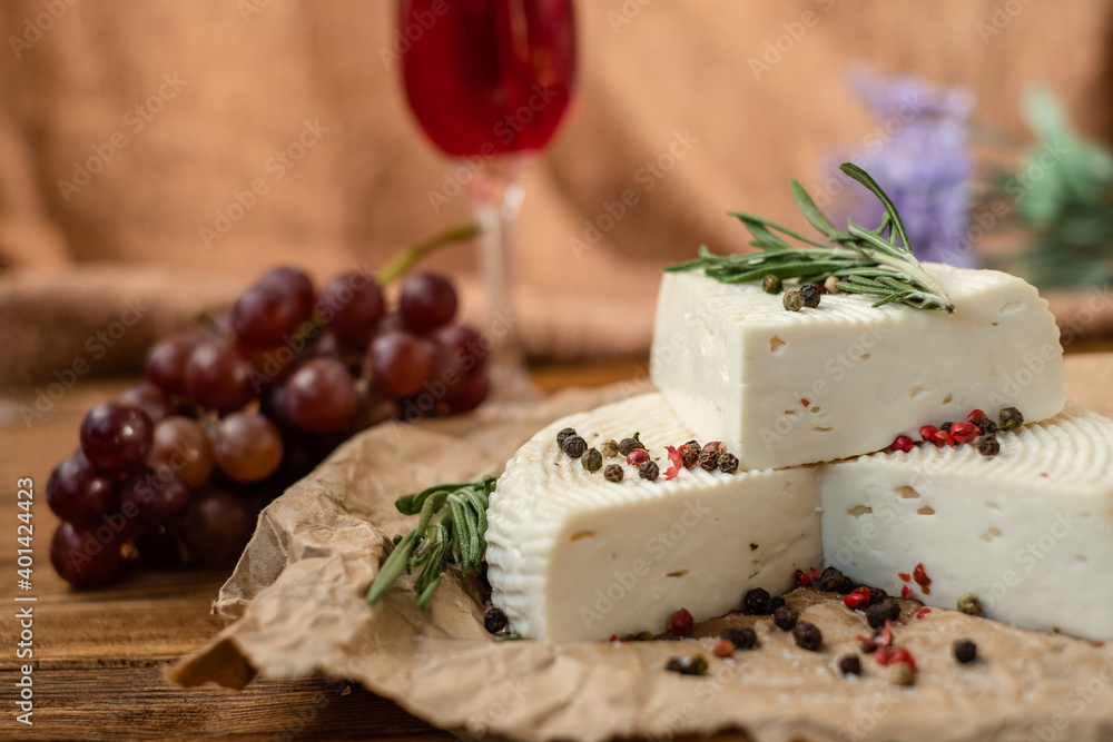 Goat cheese, grapes and wine lie on a wooden table. Cheese at home.