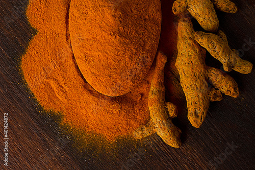 Turmeric powder and root on a wooden table, top view. no people,