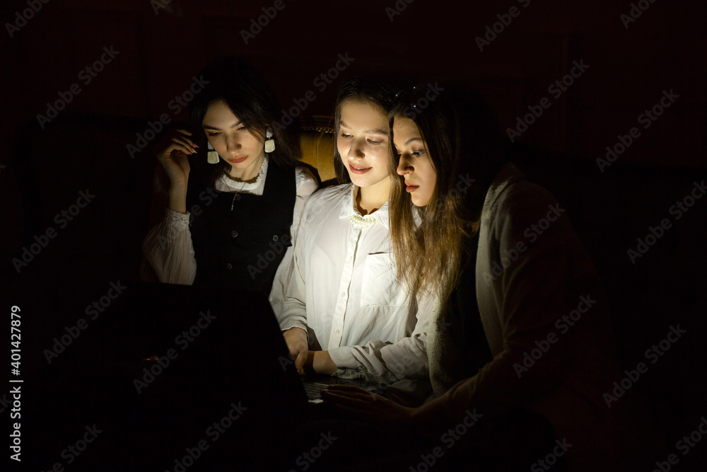 three young women at night at the laptop three young women at night at the laptop