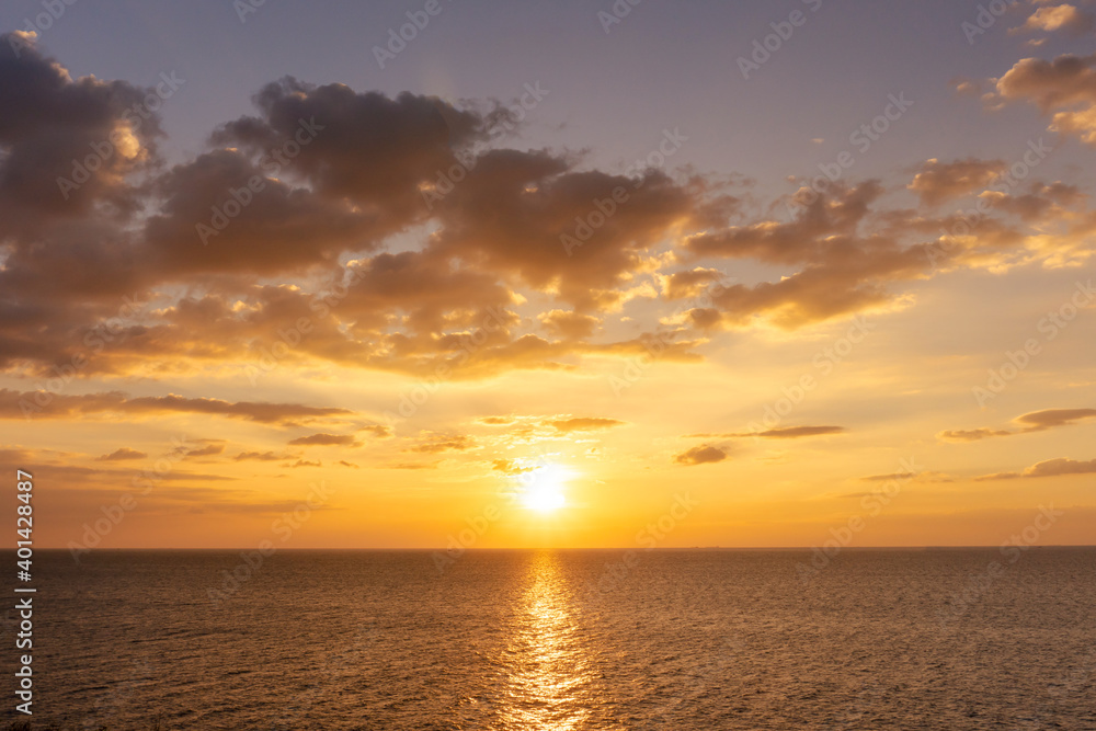 Sunset reflection ocean. beautiful sunset behind the clouds and blue sky above the over ocean landscape background