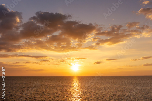 Fototapeta Naklejka Na Ścianę i Meble -  Sunset reflection ocean. beautiful sunset behind the clouds and blue sky above the over ocean landscape background