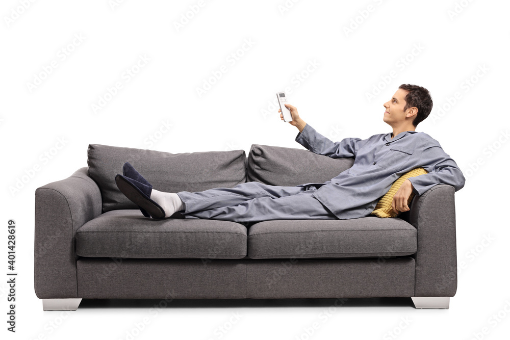 Man in pajamas laying on a sofa and holding a remote control Man in pajamas laying on a sofa and holding a remote control