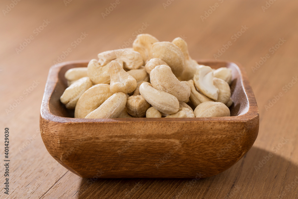 Wooden bowls of cashews on wooden table. Wooden bowls of cashews on wooden table.