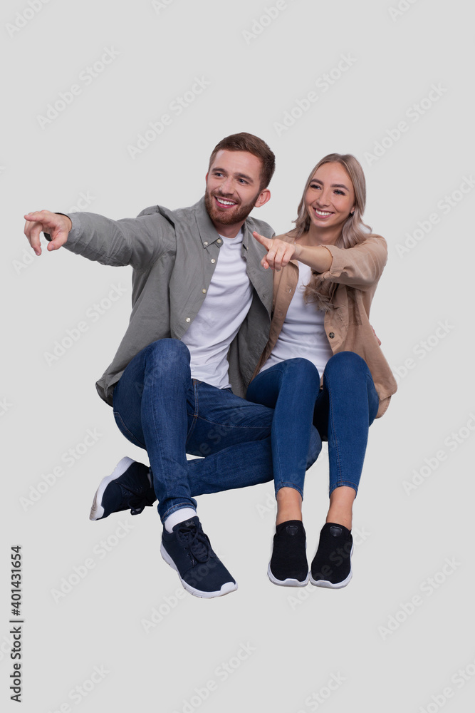 Couple Sitting on Floor Pointing to Side. Couple Isolated Watching Front. Relationship, Family, Lovers, Friends Concept Couple Sitting on Floor Pointing to Side. Couple Isolated Watching Front. Relationship, Family, Lovers, Friends Concept