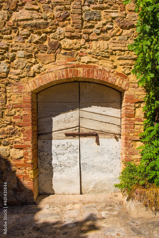 An old wooden door in an historic stone building in the village of Montorsaio in Tuscany, part of Campagnatico in Grosseto province
