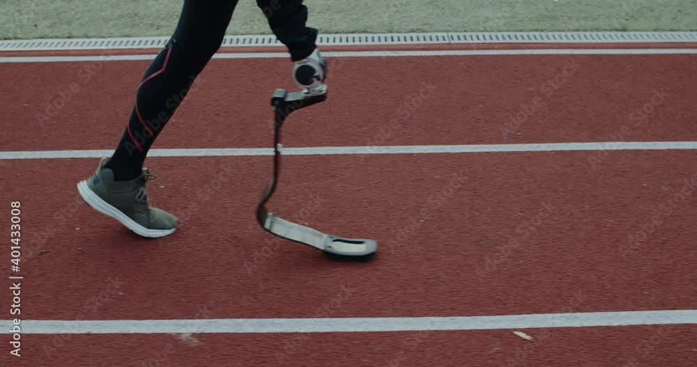 Side view of disabled male person legs with prosthetic running blade walking at sports field. Handicapped male sportsman getting ready for run. Concept of motivational sports footage. Side view of disabled male person legs with prosthetic running blade walking at sports field. Handicapped male sportsman getting ready for run. Concept of motivational sports footage.
