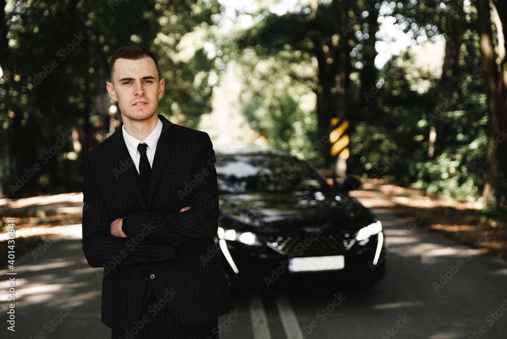 young successful businessman stands in front of his expensive car. rich young guy. rich man. car on the background of a businessman. groom with car on wedding day young successful businessman stands in front of his expensive car. rich young guy. rich man. car on the background of a businessman. groom with car on wedding day