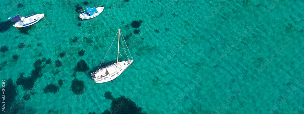 Fototapeta premium Aerial drone ultra wide photo of traditional fishing boat and yacht anchored in paradise bay of Ornos, Mykonos island, Cyclades, Greece