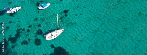 Aerial drone ultra wide photo of traditional fishing boat and yacht anchored in paradise bay of Ornos, Mykonos island, Cyclades, Greece