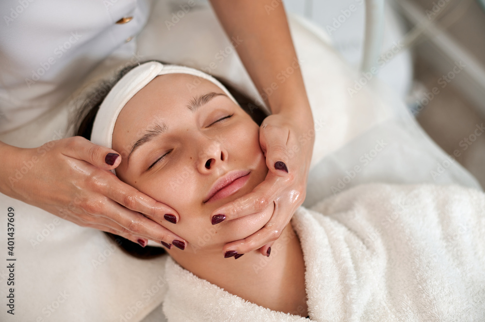 Cosmetologist making lifting facial massage for woman's face and neck. Closeup Cosmetologist making lifting facial massage for woman's face and neck. Closeup