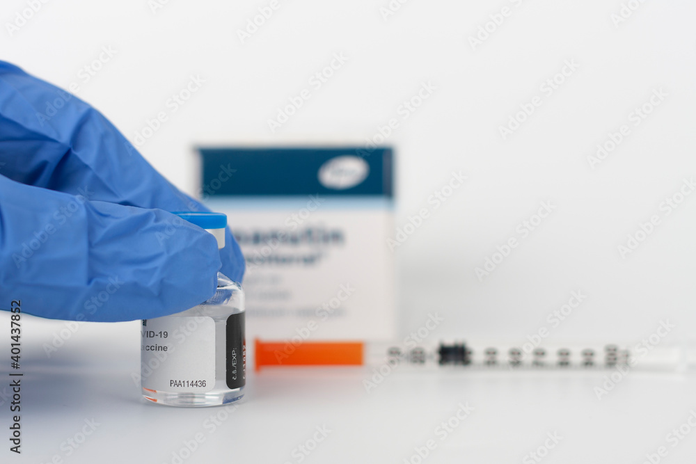 Obraz premium Human fingers in gloves, syringe with needle, vial and paper box with Covid-19 vaccines.