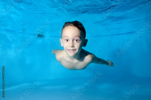 Portrait of a beautiful athletic boy underwater in the pool. Fun dives under the water. Swimming classes. Bodily exercises. Healthy lifestyle