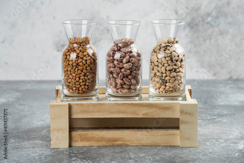 Three glasses of jar with unprepared beans on a gray background photo