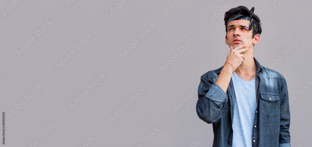 Young man thinking in casual shirt isolated over gray background Young man thinking in casual shirt isolated over gray background