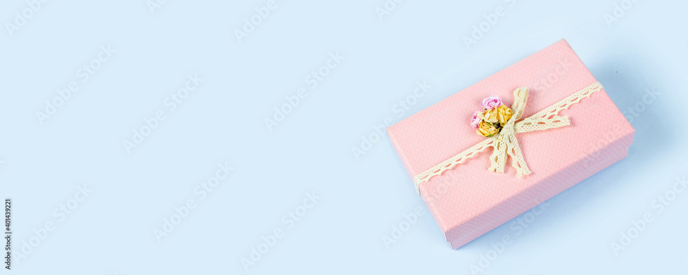 Beautiful pink gift box isolated on blue background. Copy space. Banner.